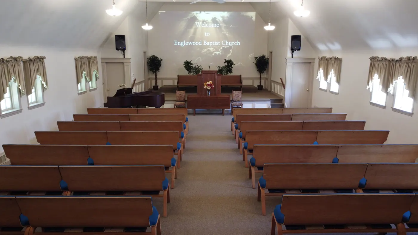 Inside the sanctuary at Englewood Baptist Church: wooden pews, a pulpit and a screen reading Welcome to Englewood Baptist Church